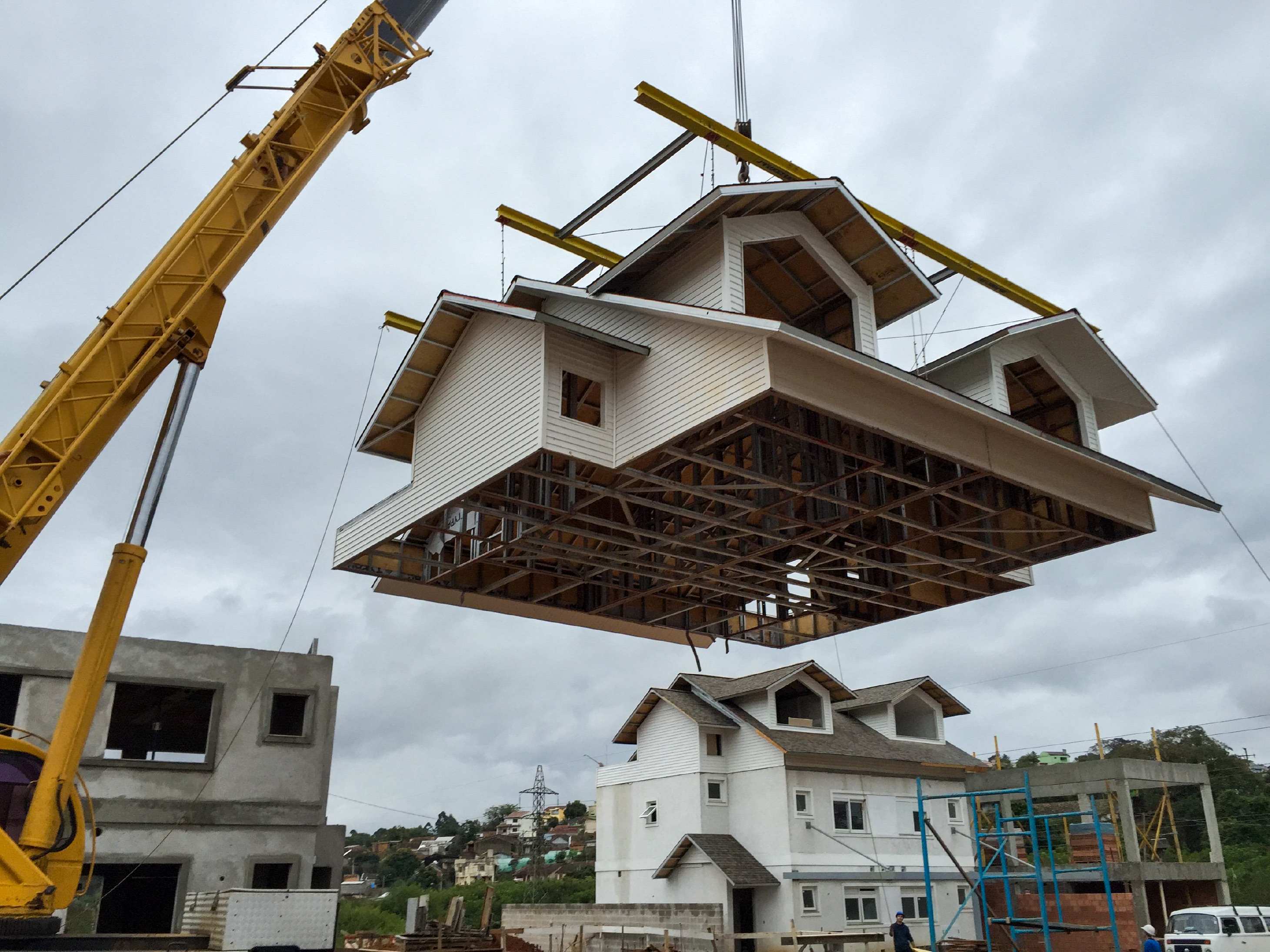 Casa modular sendo içada por guindaste durante construção industrializada